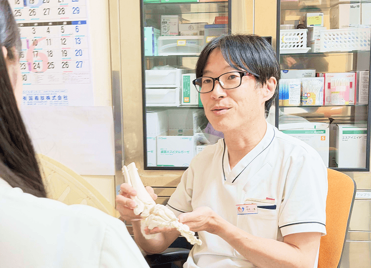 足の模型で患者さんに説明する院長